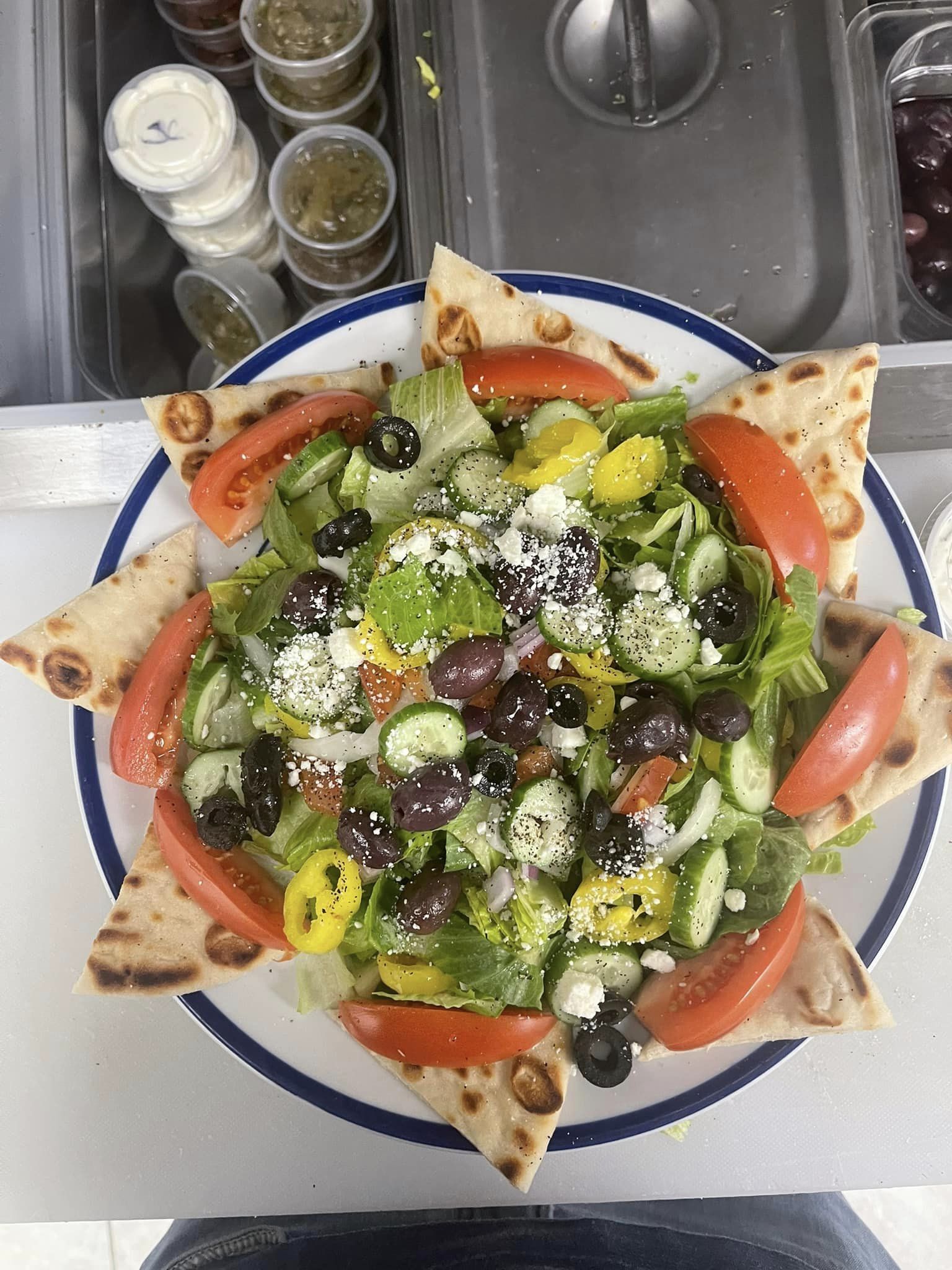 Dressed Greek salad inside ring of triangular pita slices