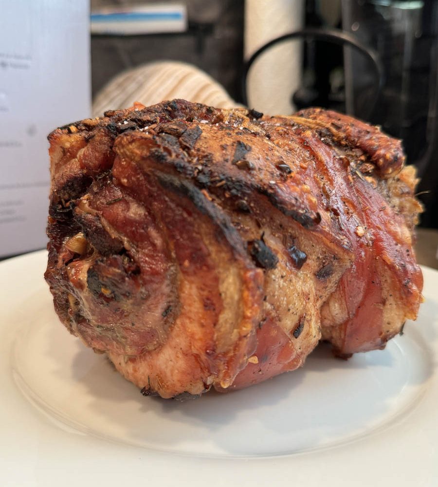 Roasted porchetta plated on white plate.