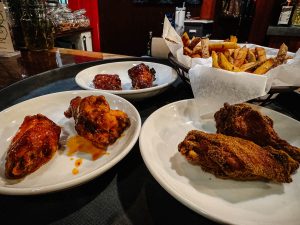 Array of wings in three different sauces with basket of French fries, served at O'Huid's Gaelic Pub in Lancaster, Ohio.